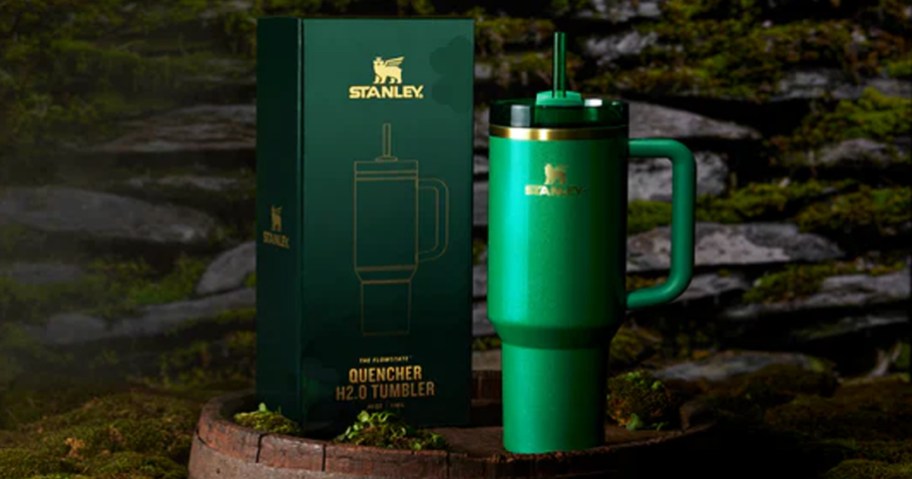 green stanley tumbler and its box on top of a barrel