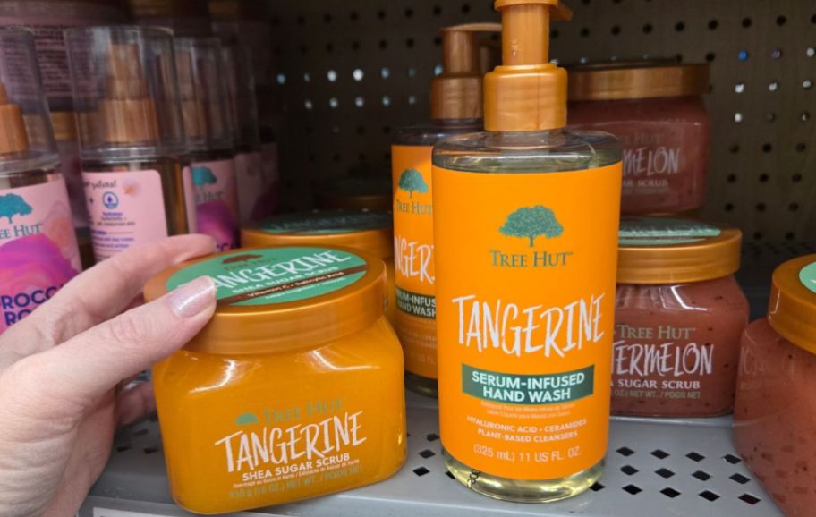 a womans hand holding a jar of tangerine sugaR SCRUB NEXT TO A BOTTLE OF hand wash