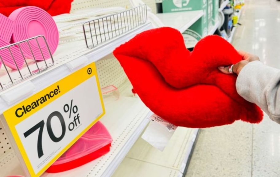 womans hand holding a red lip shaped pillow next to a price scanner