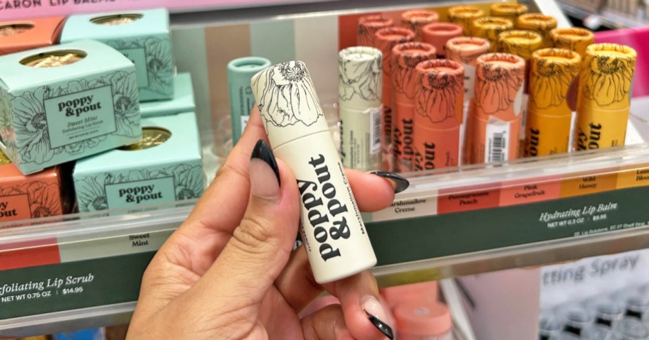 hand holding a tube of Poppy & Pout Lip Balm in store