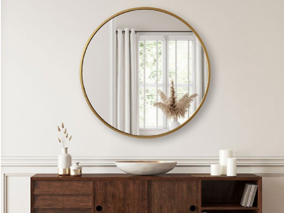 Gold round mirror displayed on top of a side table