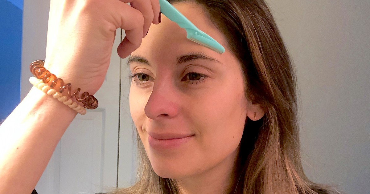 woman smiling holding up blue razor on forehead