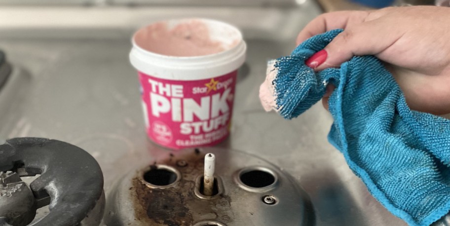 hand holding microfiber blue towel over stove with the pink stuff cleaner