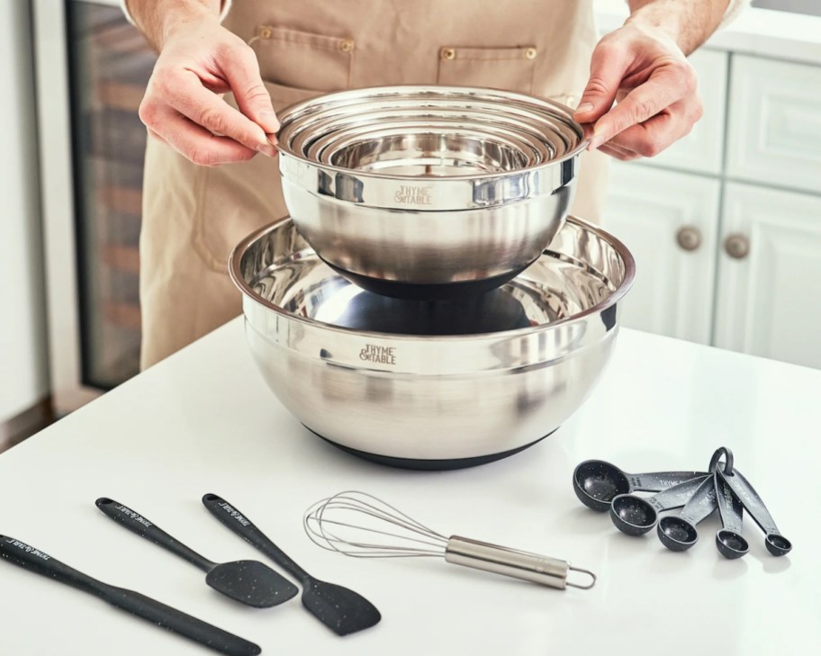 person with apron holding collection of nesting stainless steel bowls