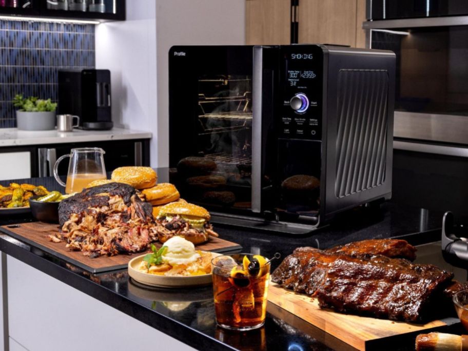 GE Profile Smart Indoor Pellet Smokers surrounded by plates of smoked meats