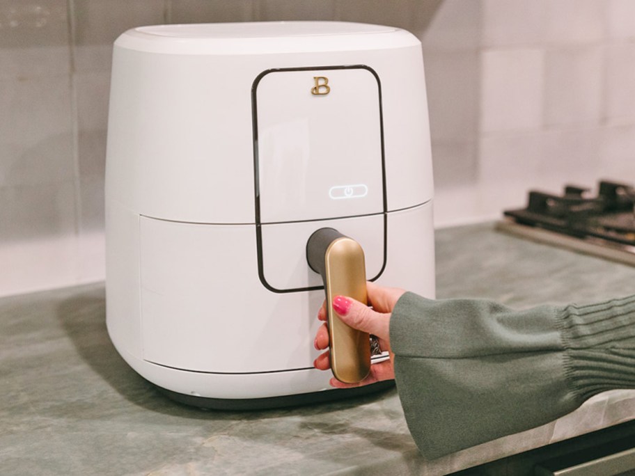 hand grabbing handle on white drew barrymore air fryer