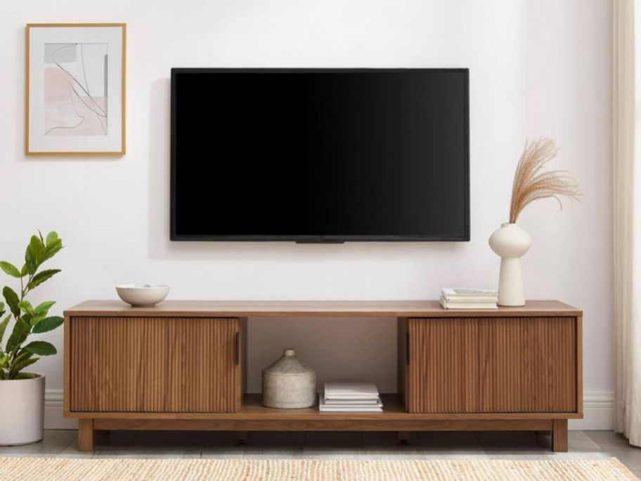 Welwick Designs Mid-Century Modern TV Stand w/ 2 Reeded Doors in living room with tv hanging above it