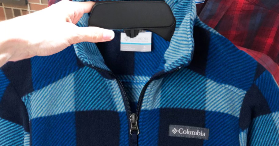 hand holding up a blue plaid fleece on hanger in store