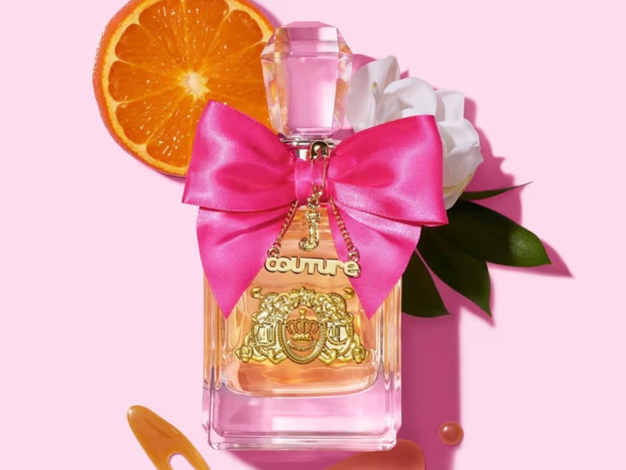 bottle of Juicy Couture Viva La Juicy with pink bow near orange slices, flowers, and honey