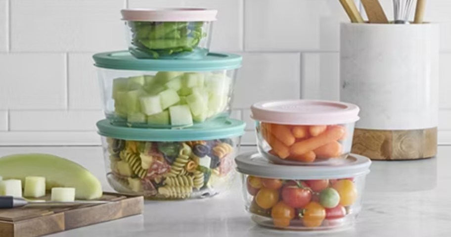 2 stacks of round glass Pyrex food container bowls with pastel lids on a kitchen counter