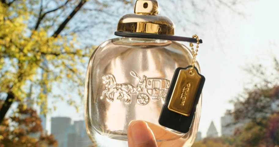 hand holding coach fragrance bottle 