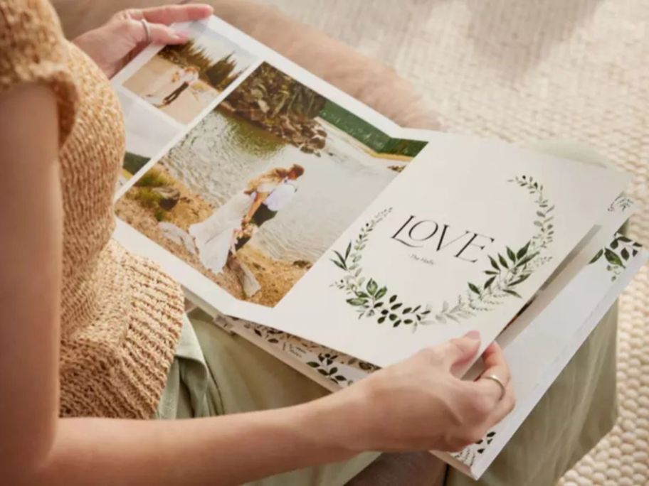 Woman looking at a Shutterfly photo bokk with the word love on one page and a couple on the other