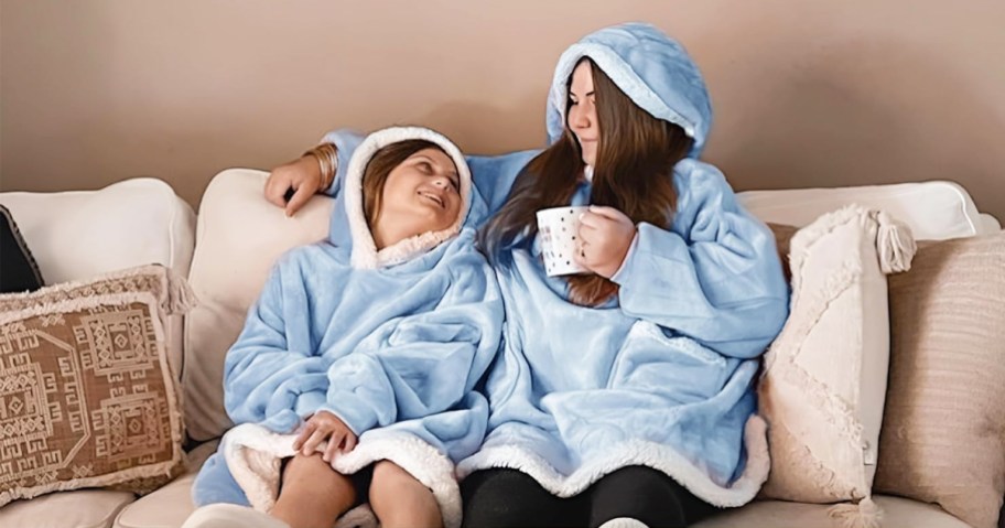 mom and daughter sitting on couch in blue wearable blankets