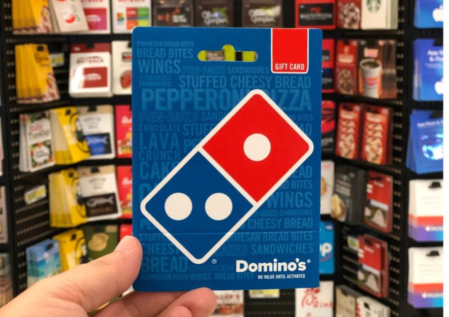 a mans hand holding a dominos gift card