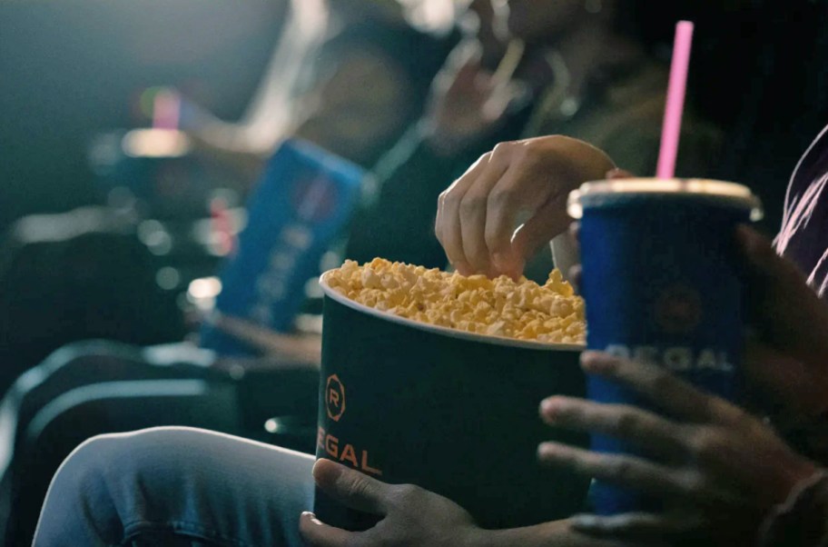 people watching movie and holding buckets of popcorn and drinks