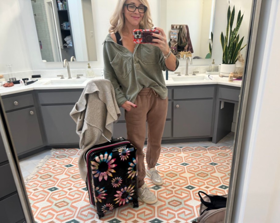 woman taking selfie in bathroom mirror travel packing hacks