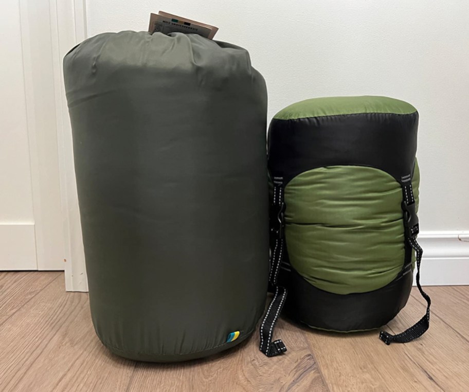 compression sacks with sleeping bags and clothes sitting on wood floor travel packing hacks