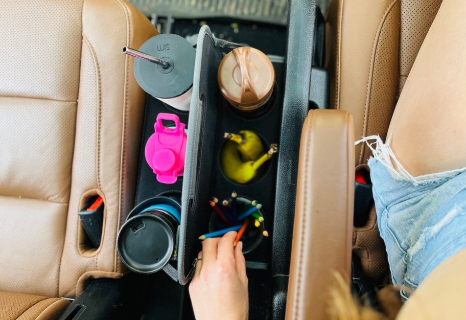 car cup holder between seats in car with cups and snacks