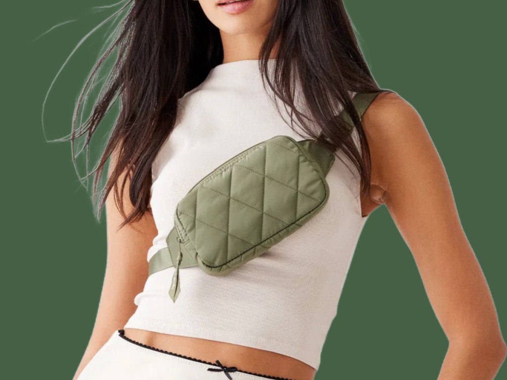 Woman wearing green vera Bradley belt bag across body with white sleeveless tank to