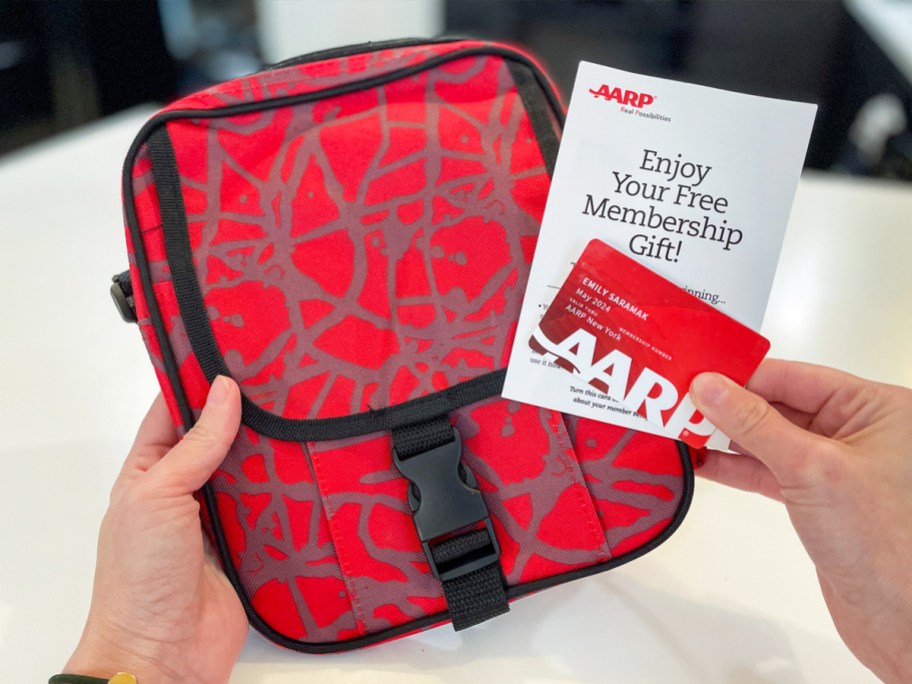 hands holding up a red crossbody bag and AARP cards