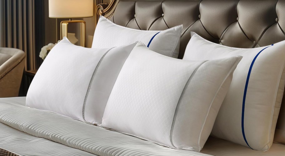 4 white hotel style pillows on a bed