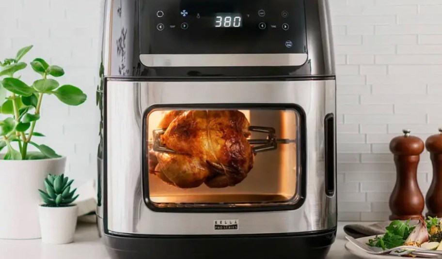 silver and black bella air fryer on counter with chicken cooking inside