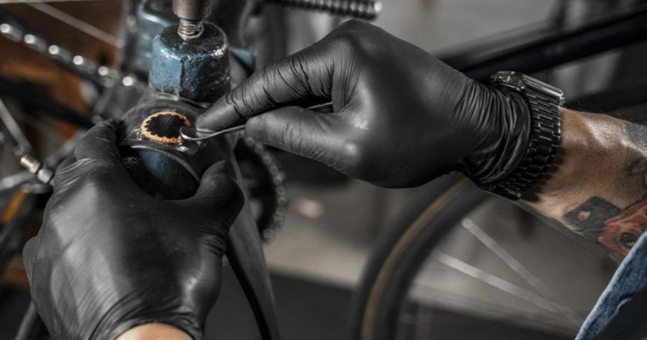 A person wearing Black Disposable Gloves to fix a machine