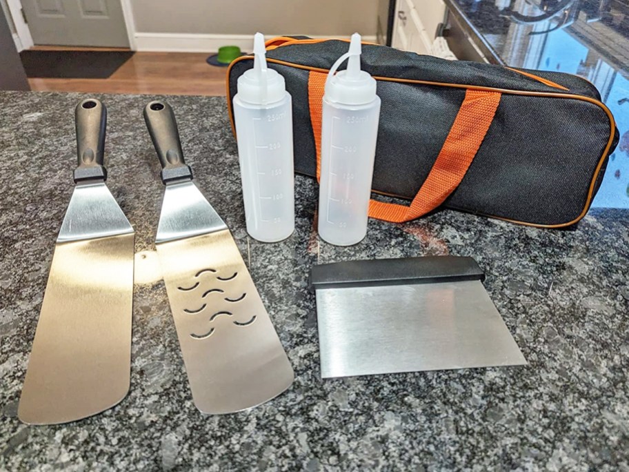 two large spatulas, scraper, squeeze bottles, and bag on kitchen counter