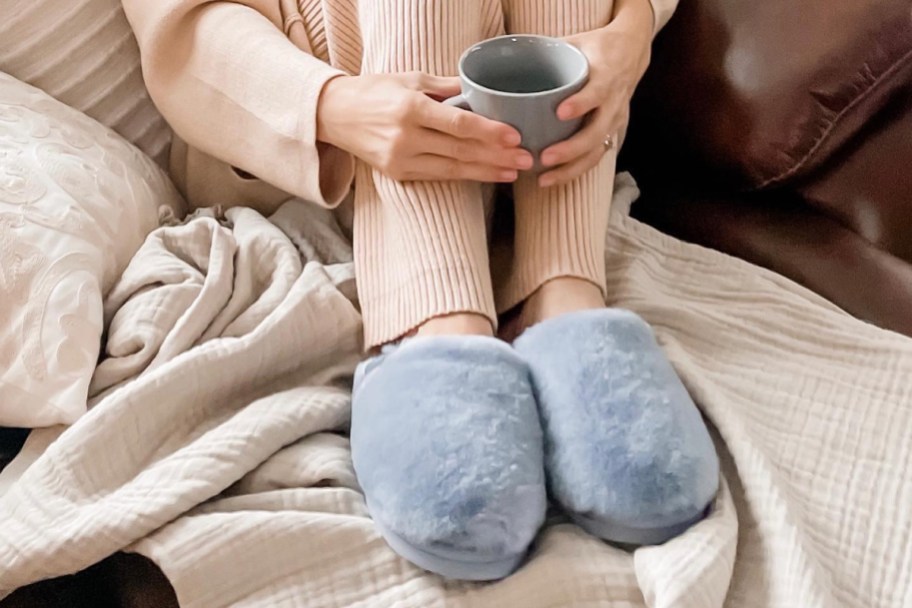 hands holding coffee wearing pair of slippers