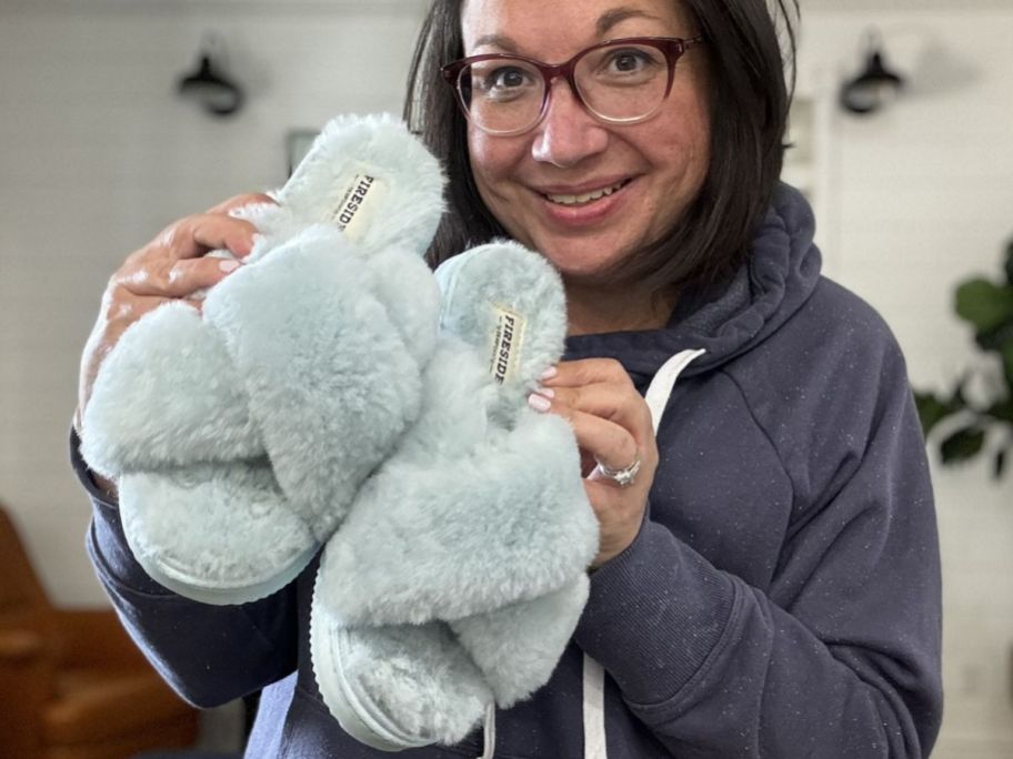 Woman holding a pair of Dearfoam's Fireside Sliippers