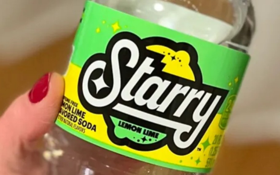 a womans hand holding a bottle of starry soda