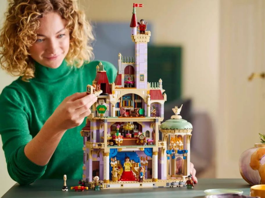 A woman playing with a LEGO Beauty and the Beast Castle