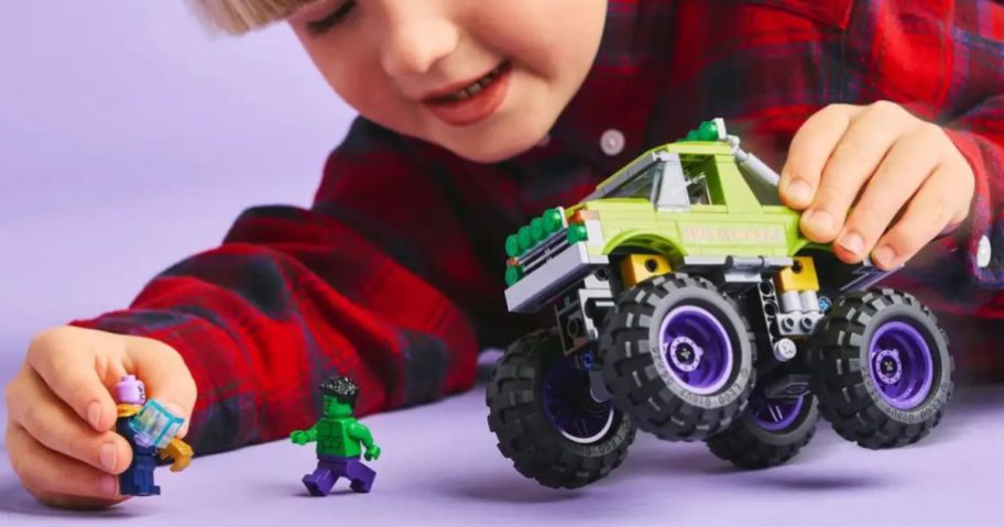 A little boy playing with LEGO Hulk vs Thanos