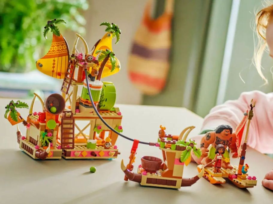 A little girl playing with LEGO Disney Moana Kakamora Barge