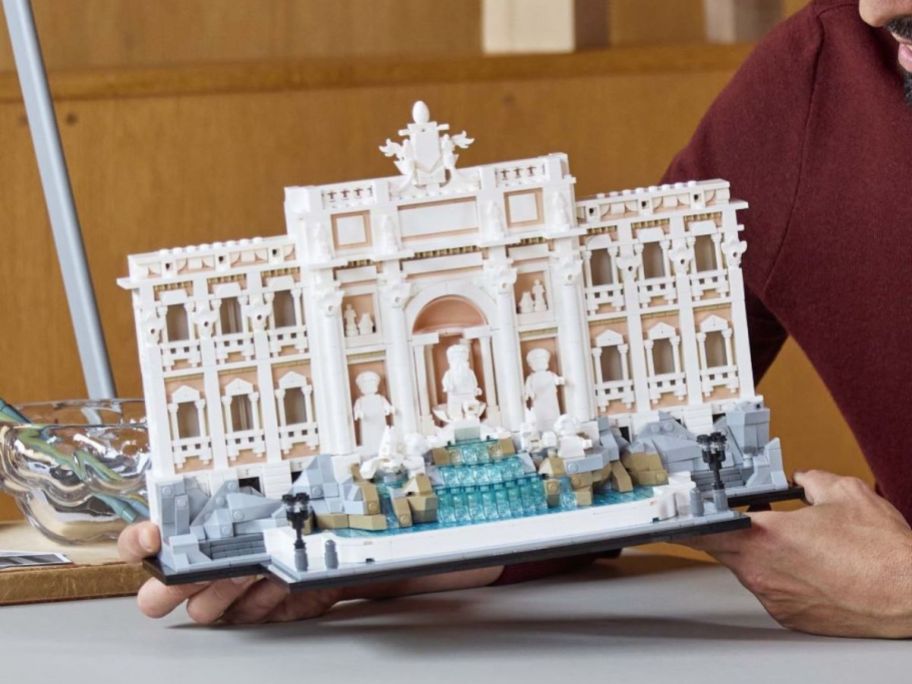 person holding LEGO Trevi Fountain on table