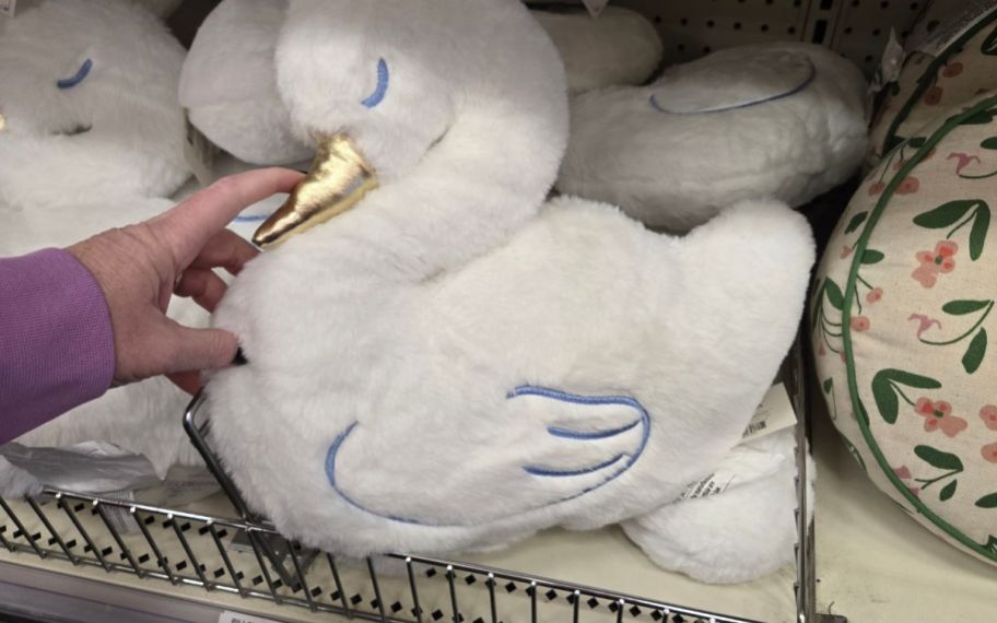 a womans hand holdinga white swan pillow