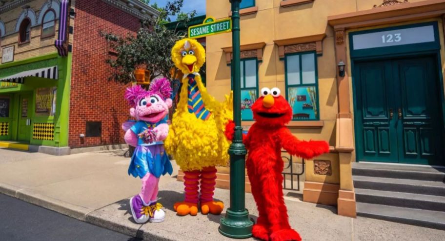 Abby, Elmo and big bird standing in front of their Sesame Street sign