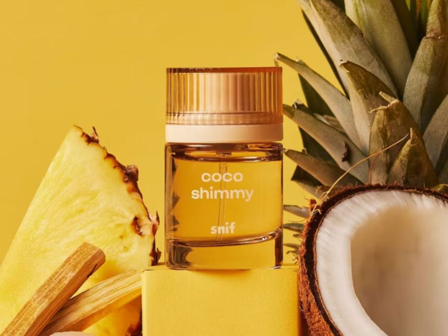 Snif Coco Shimmy Eau de Toilette amongst a pineapple slice and a sliced coconut