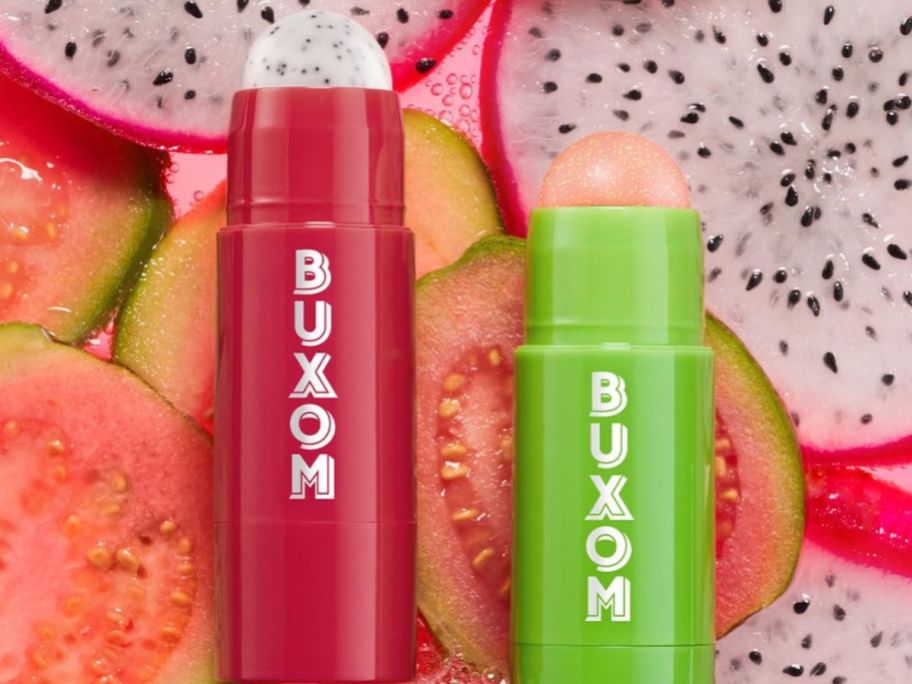 Two Buxom Power-full Lip Scrub s surrounded by dragonfruit and guava