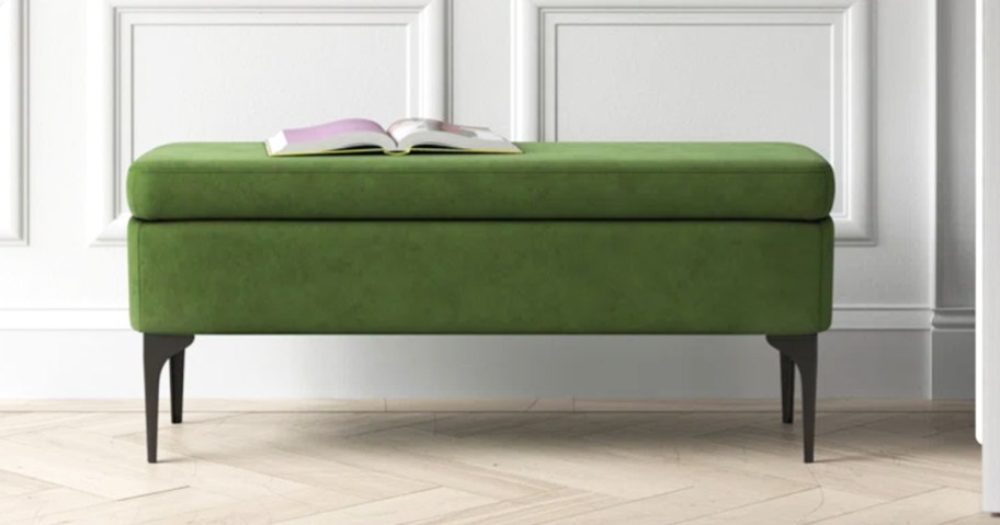 green upholstered bench with book on top