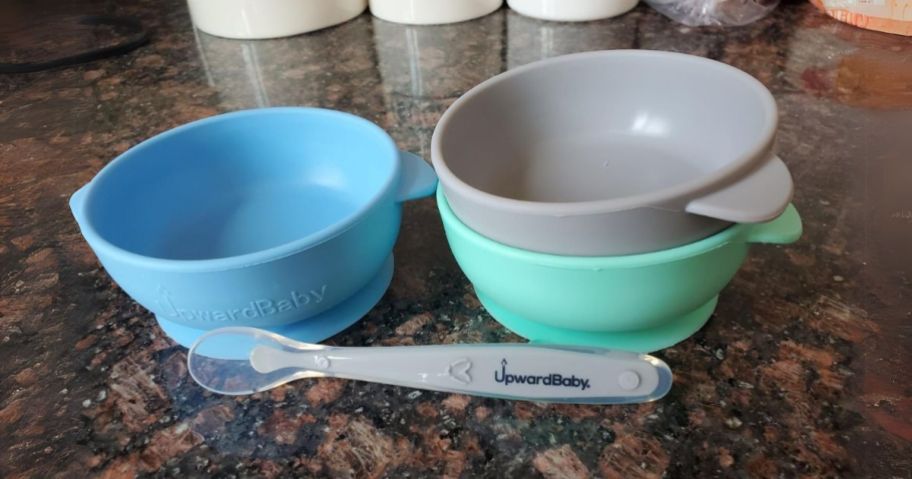 a set of 3 Silicone Bowls and a baby feeding spoon on a kitchen counter