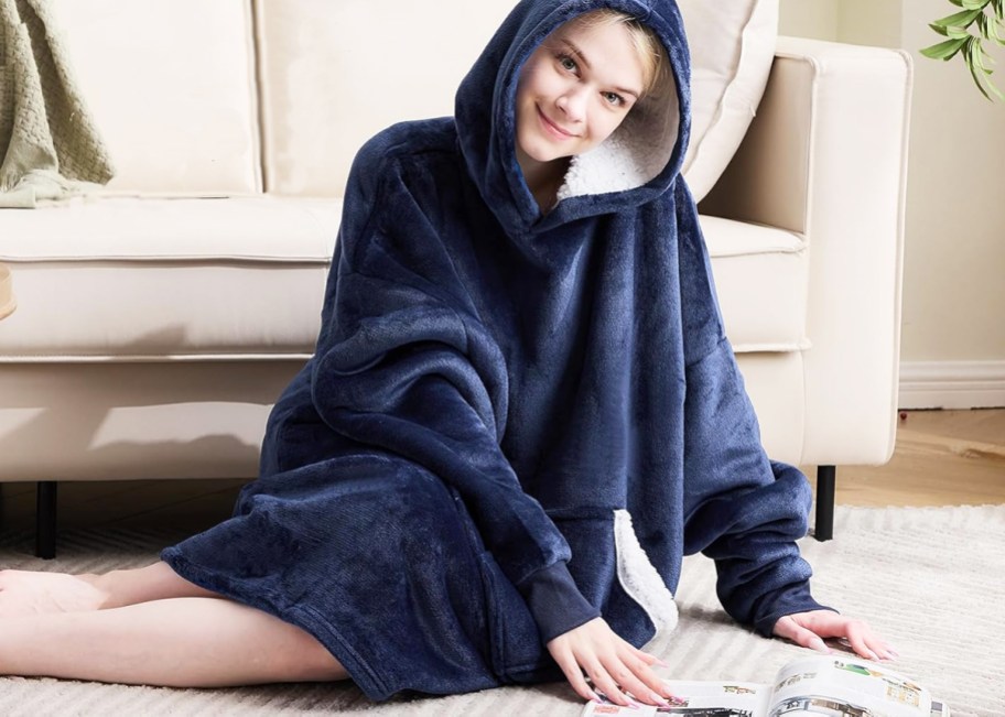 woman sitting on floor wearing a navy blue hooded wearable blanket