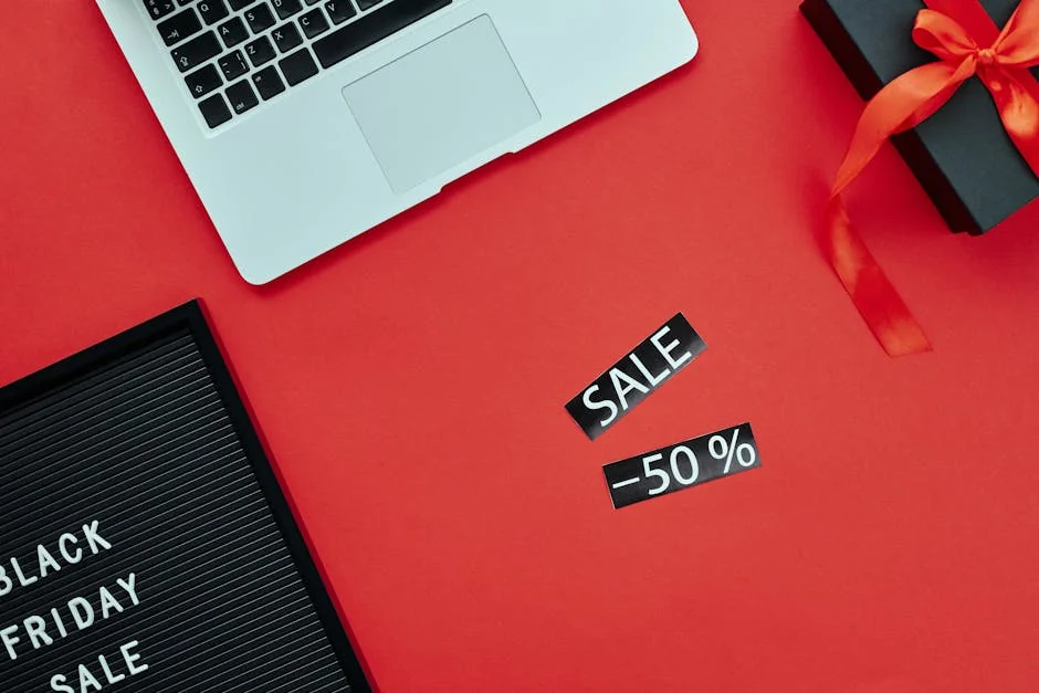 Overhead view of a laptop and gift box on a red surface with Black Friday sale sign. - cyber monday early access deals for subscribers