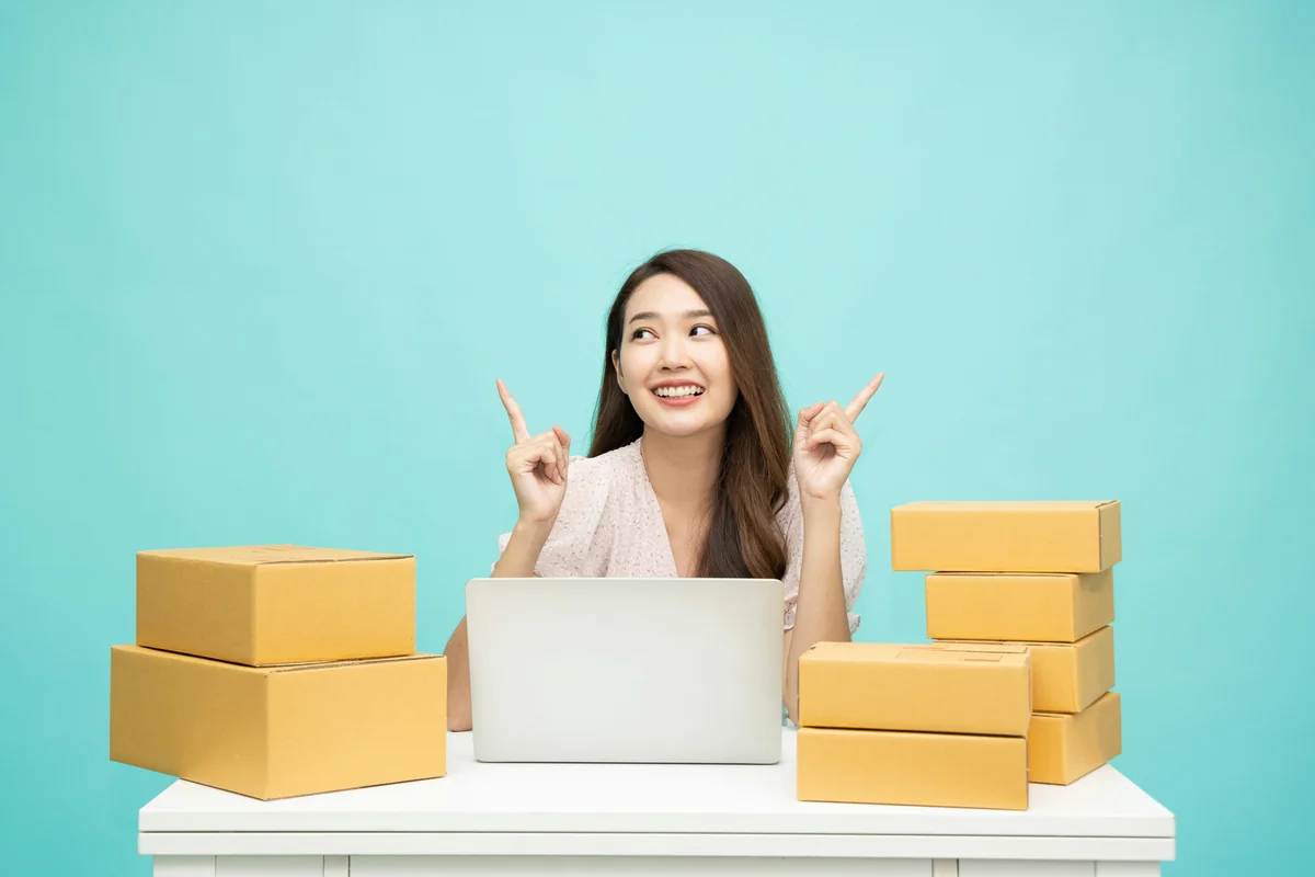 a woman sitting at a table with a laptop surrounded by boxes - how to get free shipping on international orders