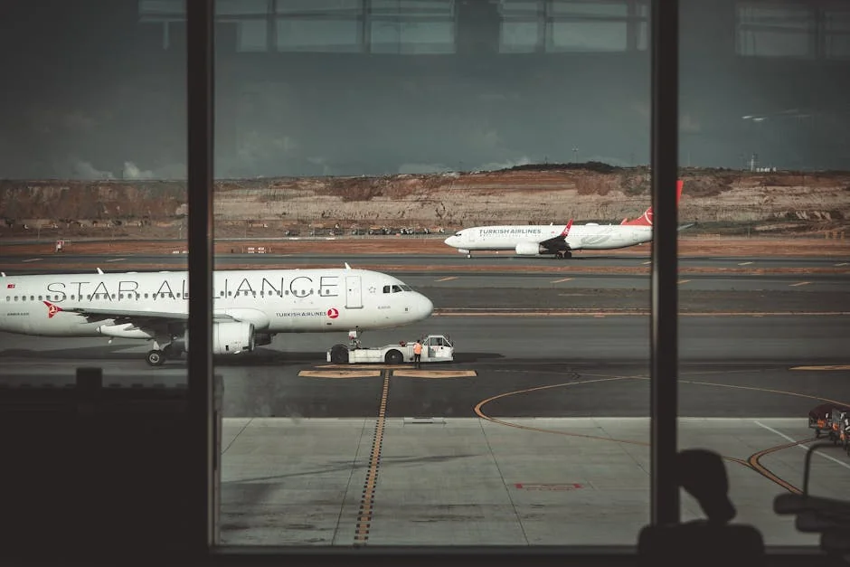A view through airport windows showing airliners on the runway, creating a travel ambiance. - airplane travel airport - Last minute flight deals and hotel voucher codes