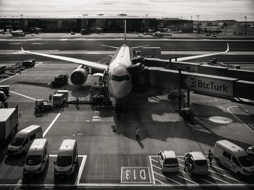 Monochrome image of airplane at airport gate with vehicles and jetway during the day. - airplane travel airport - Last minute flight deals and hotel voucher codes