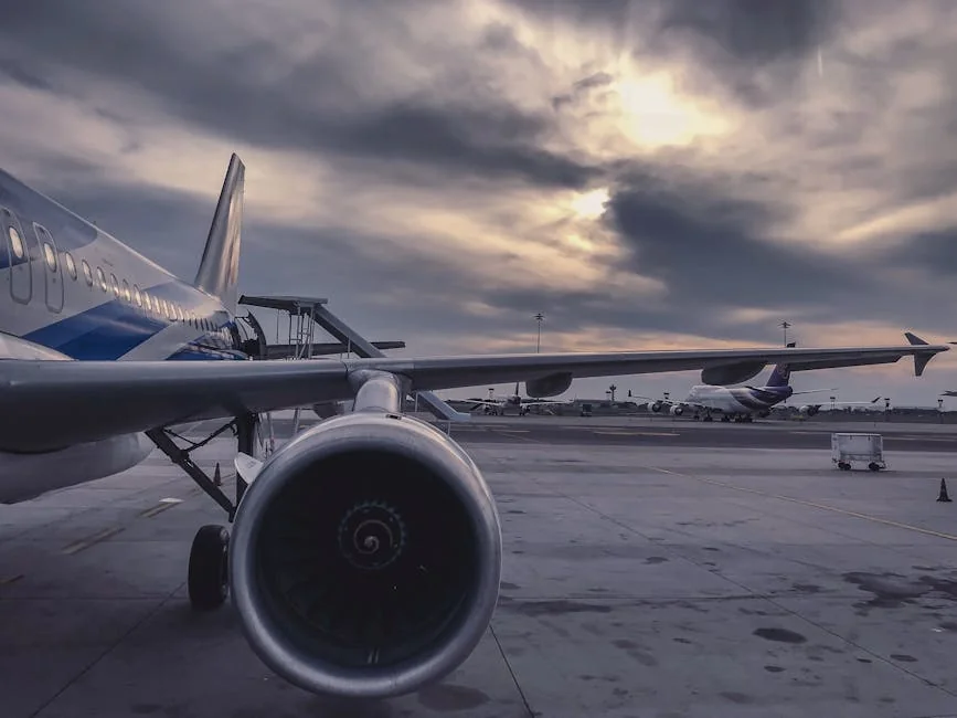 A passenger airplane is parked on the tarmac at sunset, with another aircraft in the background. - airplane travel airport - Last minute flight deals and hotel voucher codes
