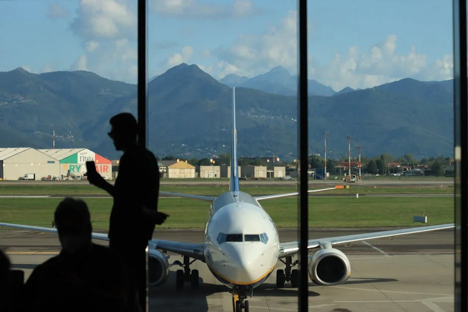 A silhouette of a person at Bergamo airport, overlooking a parked airplane with mountain backdrop. - airplane travel airport - Last minute flight deals and hotel voucher codes