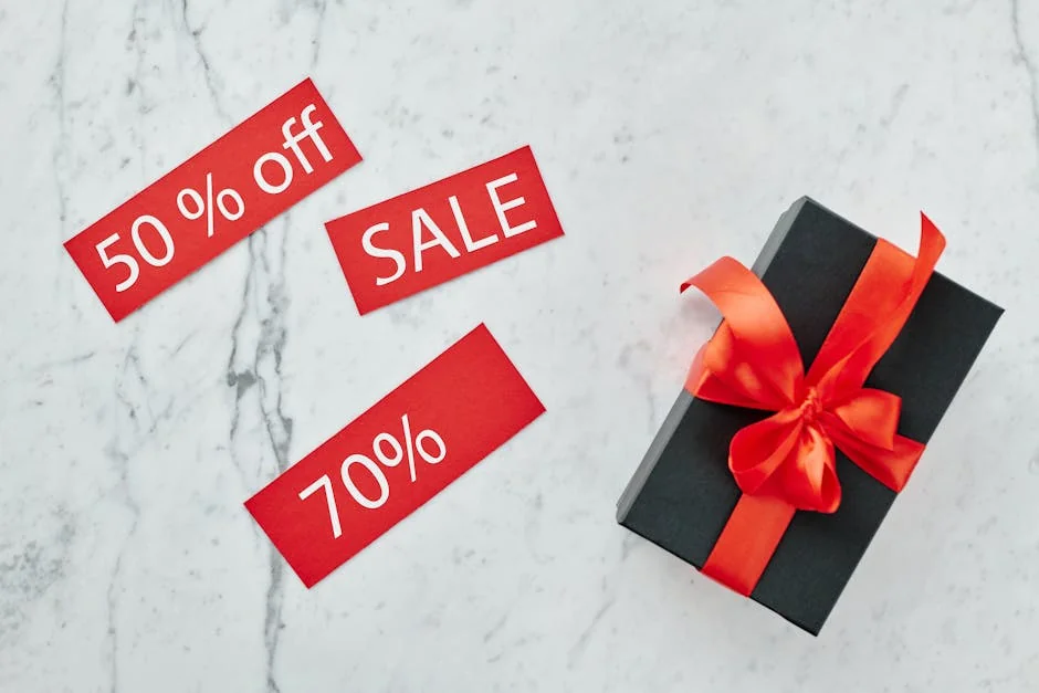 Stylish black gift box with red ribbon and sale tags on marble, perfect for Black Friday promotions. - limited time luxury fashion sales online