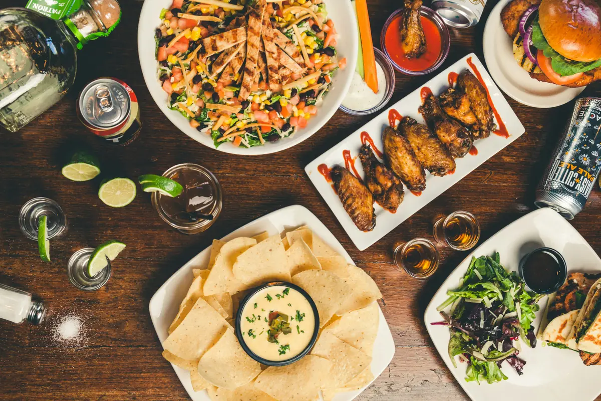 A whole bunch of food that got cold. Shots of tequila, salads, burgers with satanic pineaples, lots of spilled salt and some more tequila. Looks like someone forgot to drink that beer. Part of the C9 Work WordPress Theme sample content imagery. - local restaurant coupons and dining out deals